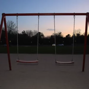 Empty swings in a quiet park at dusk.